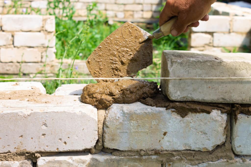 The bricklayer applies mortar to the wall with a trowel. Technology of laying buildings from cement.
