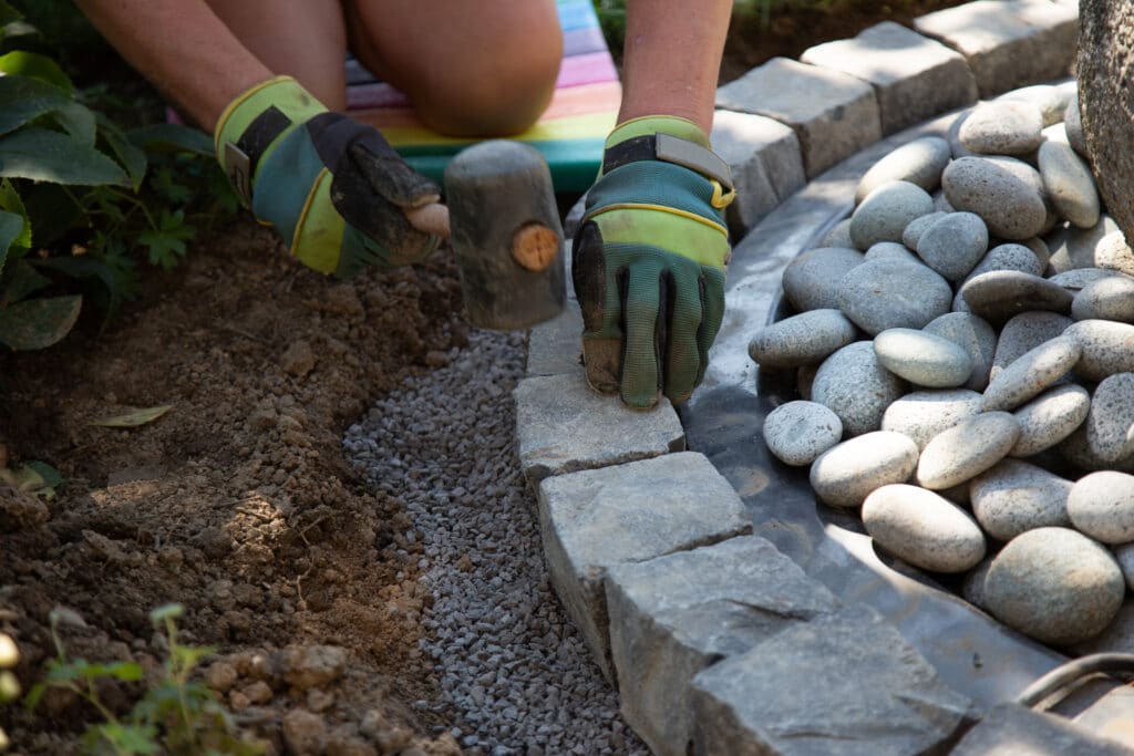 A closeup shot of a handyman arranging cobblestones using a mallet